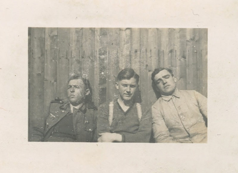 Three men sitting in a row with one man leaning on the other.