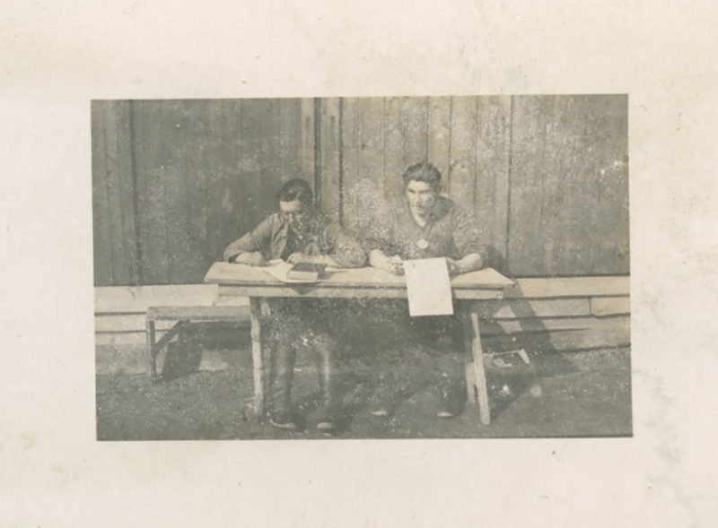 Two men sitting at a table with papers on it.