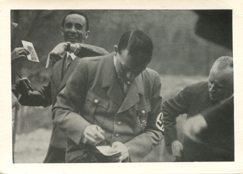 A man in military uniform is tying his tie.