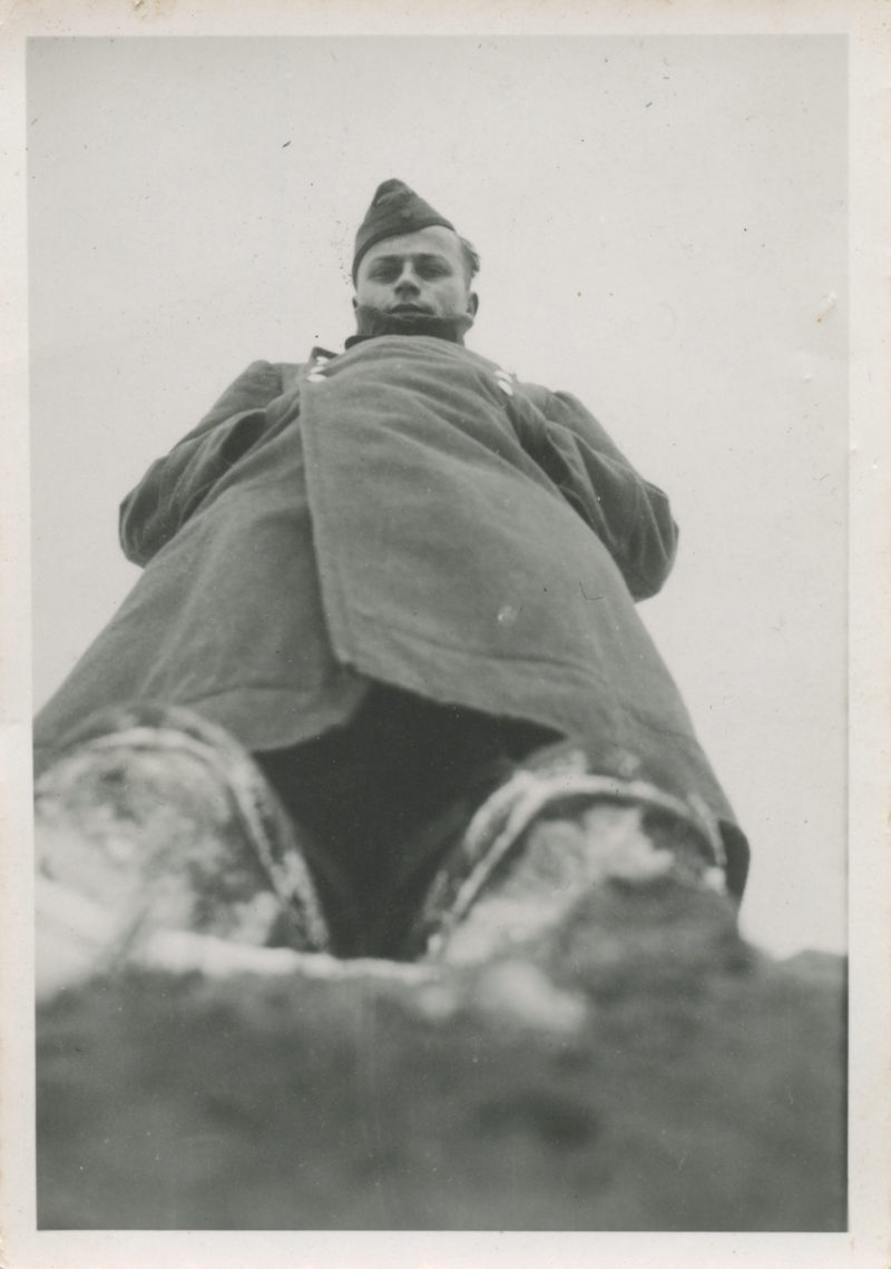 A man in military clothing sitting on top of a hill.