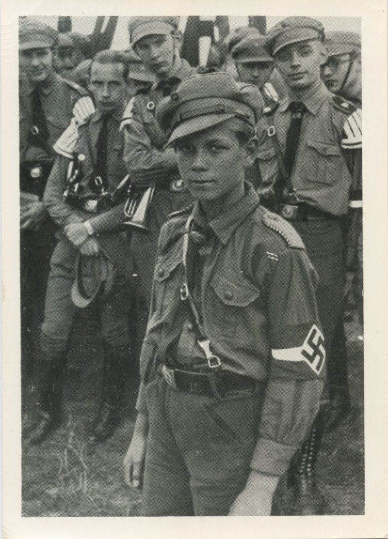 A man in uniform with other men standing around.