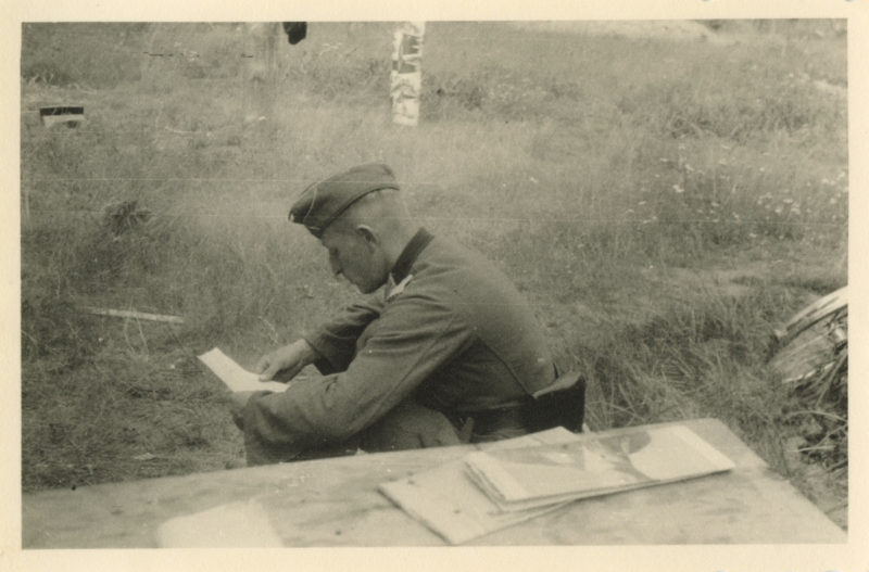 A man sitting in the grass writing on paper.