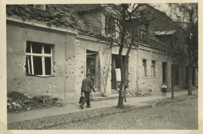 A man walking down the street in front of an old building.