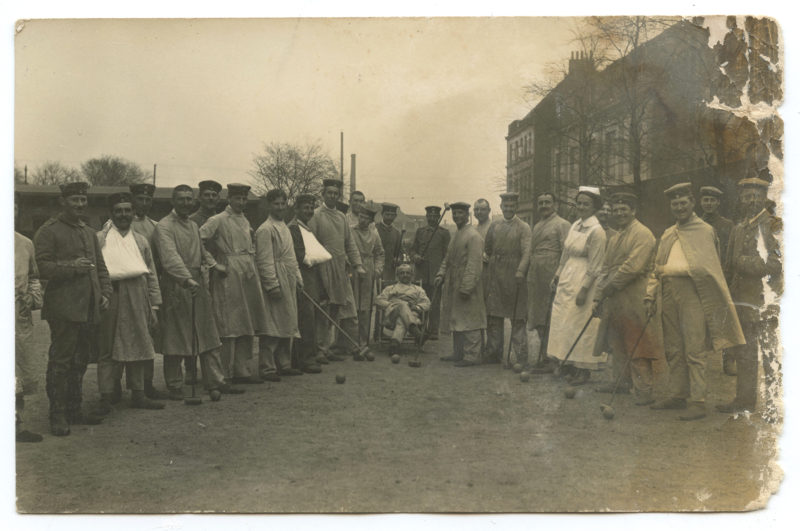 A group of men standing around in front of some buildings.