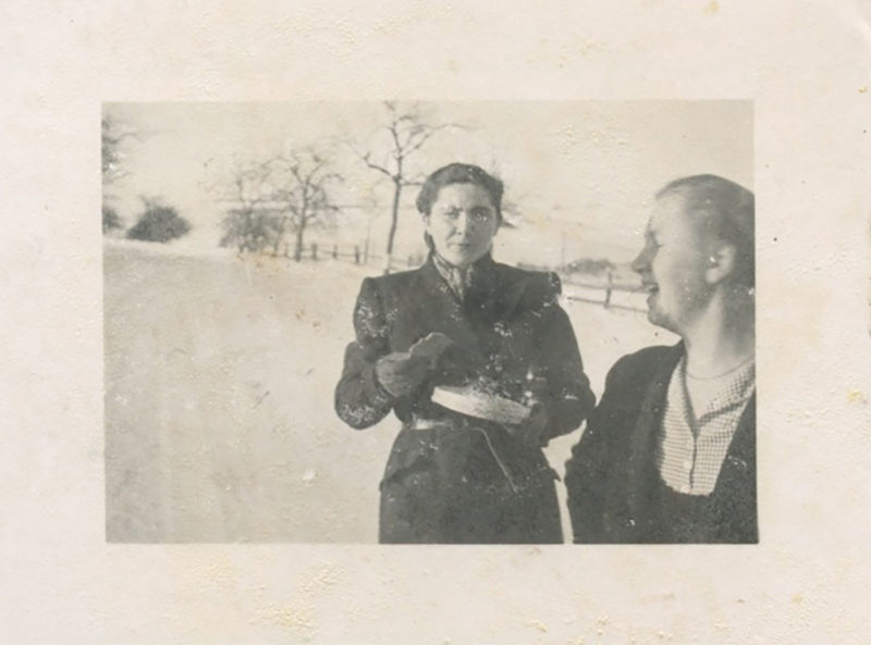 Two women standing in the snow talking to each other.