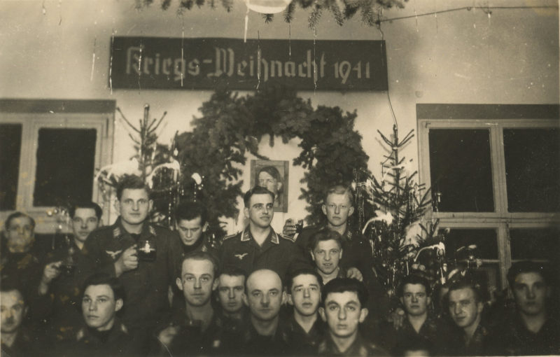 A group of men standing in front of a christmas tree.