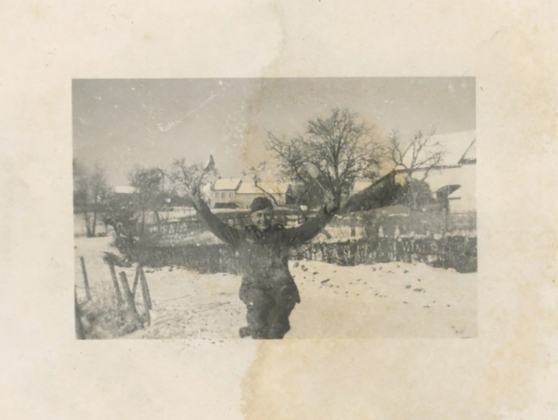 A man standing in the snow with his arms outstretched.