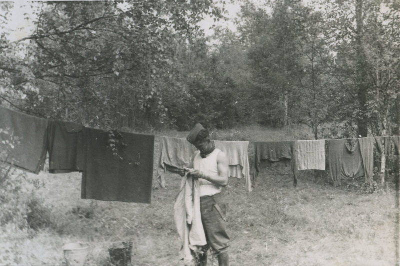 A man holding onto a rope while standing in front of clothes.