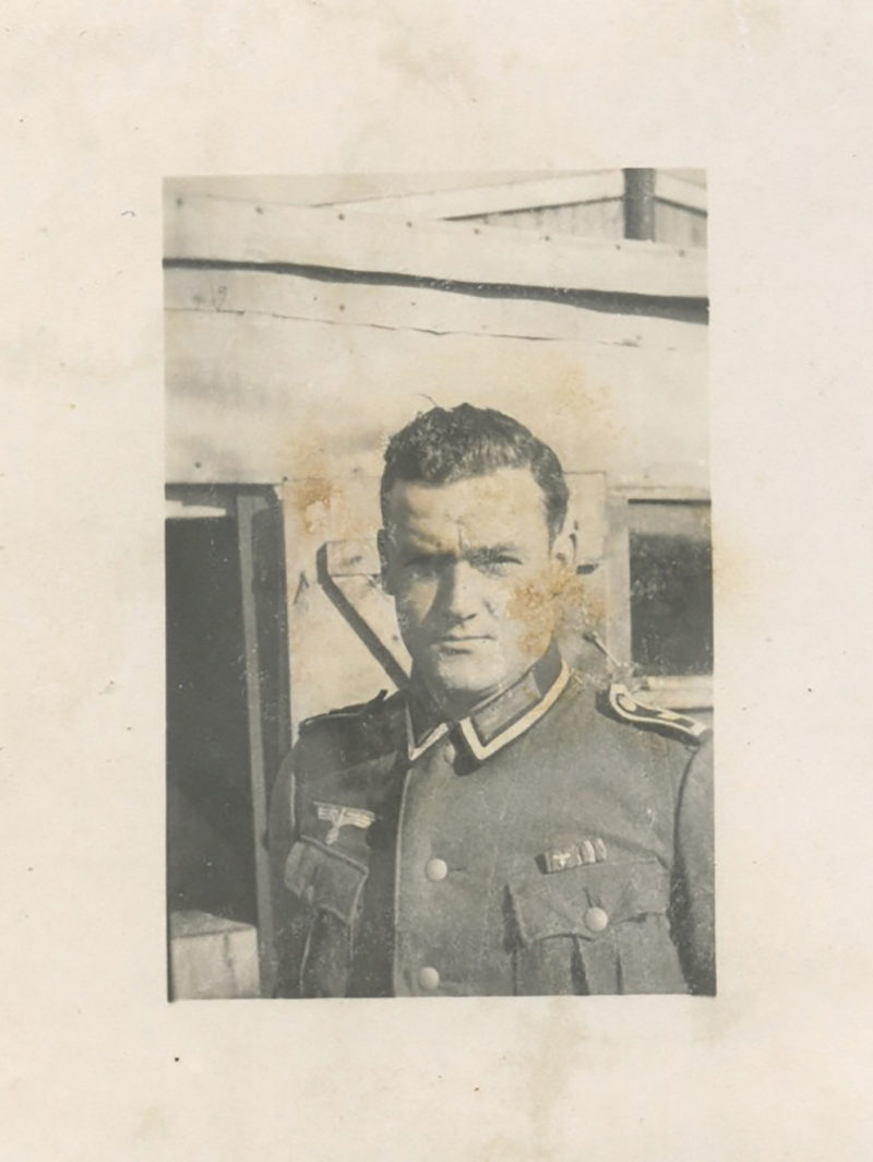 A man in military uniform standing next to a building.