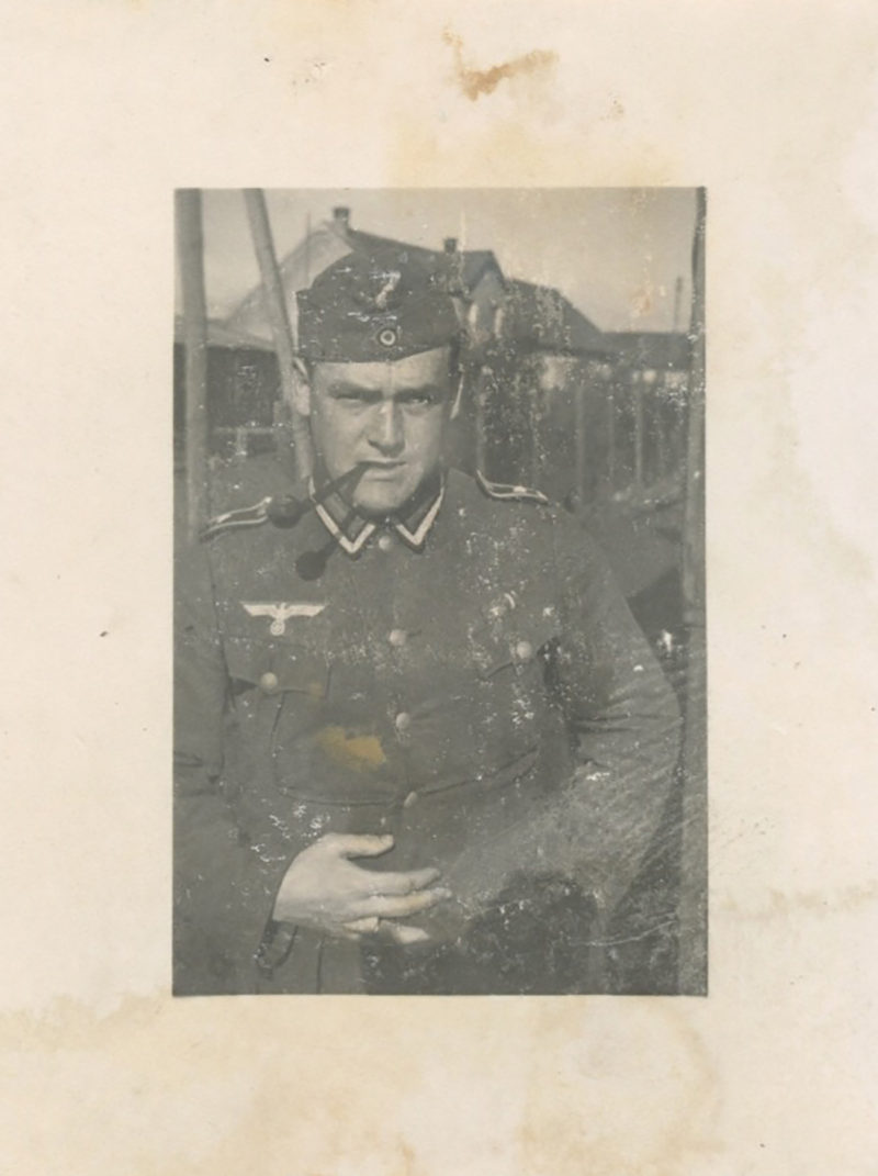 A man in uniform is standing next to a fence.