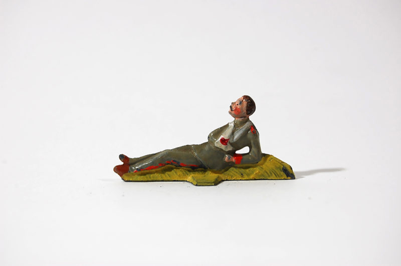 A toy figure of a man sitting on the ground.