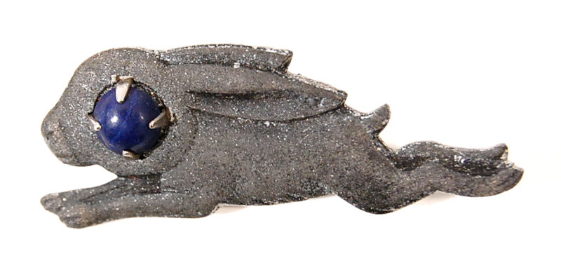 A gray dragon with blue eyes is laying down.