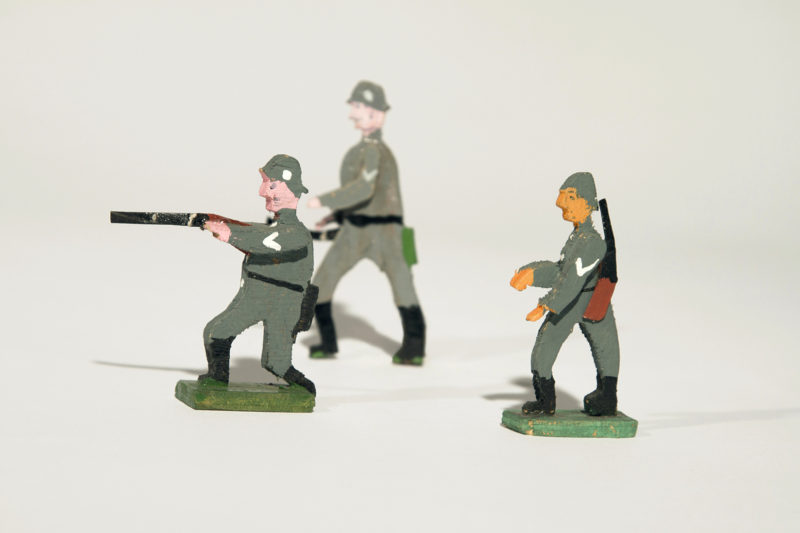 A group of toy soldiers in uniform are on the ground.