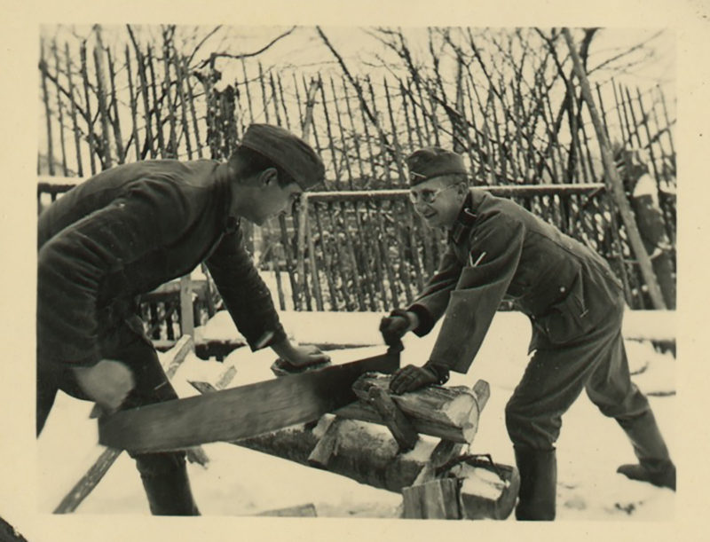 Two men working on a wooden bench in the snow.