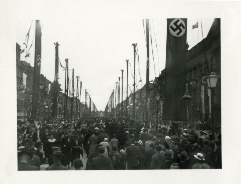 A black and white photo of people walking down the street.