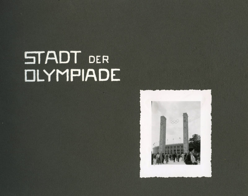 A black and white photo of two towers with the words stadt der olympiade written underneath.